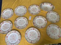 Top-down view of all eleven pieces including ten plates and one serving bowl showing overall set condition