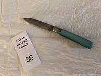 Albacete vintage penknife open, showing full blade and turquoise handle on white textured cloth background.
