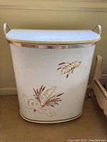 Front view of white vented clothes hamper with floral paint on front and chrome side handles.