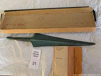 Full view of the copper spearhead with original cardboard packaging and booklet shown alongside.