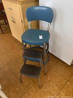 Blue vintage Cosco step stool kitchen chair with backrest and two-step black rubber textured steps showing light rust on metal parts.