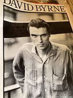 Close up photo of a black and white poster of David Byrne from 1984, showing head and shoulders portrait.