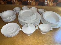 Overall view of the 45-piece white dinnerware set including plates, bowls, cups, saucers, covered sugar bowl, creamer, vegetable dish, and platter.