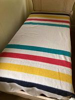 Hudson Bay Point Wool Blanket laid out on a bed showing colored stripes.