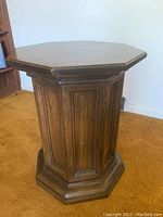 Side view of octagonal wooden pedestal side table showing paneled sides and base.