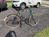 Side view of vintage Raleigh sports bicycle with black frame, chain guard, and beige tires.