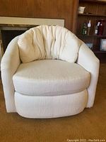 Front view of the off-white swivel barrel chair, displaying the rounded arms and plush cushioned seat and back.