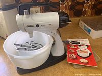Front view of Sunbeam Mixmaster stand mixer with beaters in attached bowl and separate box