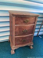 Full view of the stripped wooden nightstand showing three drawers with metal hardware and claw feet.