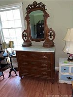 Full frontal view of the dresser showing the carved drawer fronts, marble top, and attached mirror with ornate carved supports.