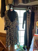 Two black patterned robes hanging in front of window