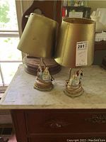 Two gold lamps with ceramic figurine bases on a marble surface, showing overall size and design