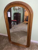 Full view of wood framed mirror showing shape, size, and condition.