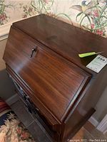 Solid wooden secretary desk closed, showing keyhole and carved detailing on front.