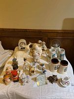 Wide view of assortment showing steins, figurines, and candles arranged on a table.