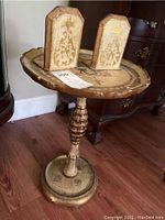 Full view of the pedestal table with two yellow wooden bookends placed on top showing the table's design and condition.