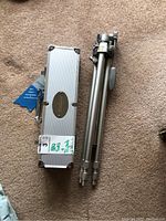 Silver metal hard case and folded tripod on carpeted floor.