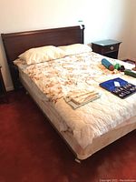 Bed with Gibbard wood headboard and adjustable metal frame on casters, covered with floral bedding, mattress included for display only.