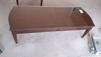 Top view of the wooden coffee table with clear glass protective top and tapered legs with metal feet showing corrosion.