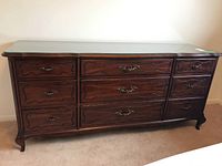 Full front view of Gibbard wooden dresser with glass top and nine drawers with metal pulls.