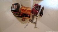 View showing faucet in original packaging, wood plane, C-clamp, measuring tape, soldering iron, adjustable wrench.