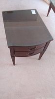 Top down view of the end table showing the glass protective top and drawer front with handles.