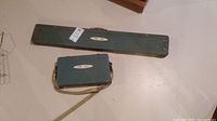 Both green carrying cases showing the long case and smaller 'Fair Isle' case together.