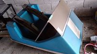 Full view of vintage blue snowmobile sled showing body and metal runners underside