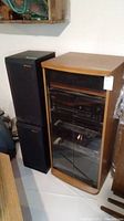 Stereo cabinet with black Sony receiver, CD player, cassette deck, and Bic speakers standing side by side