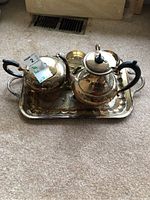 Photo showing teapot, coffee pot on ornate rectangular tray on carpeted floor