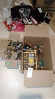 Photo showing two boxes filled with various hardware and tools on the floor.