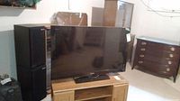 Front view of the Sony 40-inch LCD TV on a wooden surface with speakers and furniture in background.
