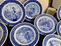 Photo showing several blue and white Rorstrand Mors Dag plates with detailed illustrations and decorative borders.