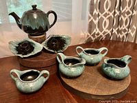 Full set of 7 pottery pieces including teapot, creamers, sugar bowls, and candlesticks arranged on a table.