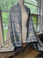 Full front view of the cashmere pashmina wrap draped on a mannequin. Shows elephant jacquard patterning with metallic bands.
