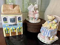Three items displayed: Tea Shop cookie jar centered and two CR Gibson Lullaby bookends flanking it showing full items' design and scale.
