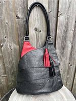 Full front view of ESPE handbag showing black vegan leather exterior with red accent and two tassels hanging from top