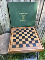 Chess board with green box lid showing The Drueke Company logo and location.