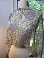Silk scarf draped over a mannequin showcasing the floral pattern and translucent quality