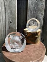 Photo shows the Mats Jonasson crystal bear intaglio and the pair of birds crystal sculpture on a wooden stump with a textured wood background, displaying the clear and frosted details of the pieces in natural light.