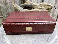 Closed view of the rectangular vintage tooled leather jewelry case with patterned leather and brass nameplate on the front
