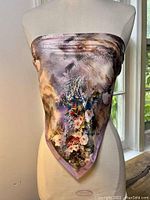 Front view of the silk scarf displayed on a mannequin, showing the overall color and floral design with handrolled edges.