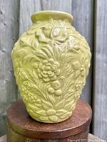 Front view of pale yellow 6.5 inch stoneware vase with embossed floral bouquet with crackle glaze.