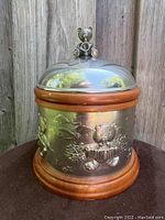 Full view of the cylindrical music box showing the wood base and top rim, pewter body with embossed bears playing instruments, and pewter lid with bear figurine handle.