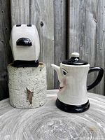 Front view of vintage clay toaster and teapot salt and pepper shakers on a wooden surface against a wood fence background.