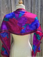 Scarf draped across dress form shoulders showing the floral pattern and color.