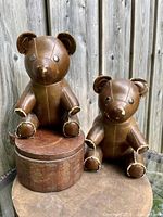 Two large brown faux leather teddy bears used as bookends, showing wear and distress on ears, paws, and noses.