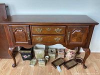 Front angle of wooden server buffet table showing two side cabinets with paneled doors and central drawers with brass hardware.