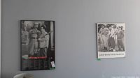Two black and white vintage style posters hanging on a wall. Left is the framed 'Who's On First?' print featuring Abbott and Costello in baseball outfits. Right is the Three Stooges 'Golf With Your Friends' plaque.