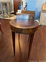 Front view of small wooden round table with lift lid box on top
